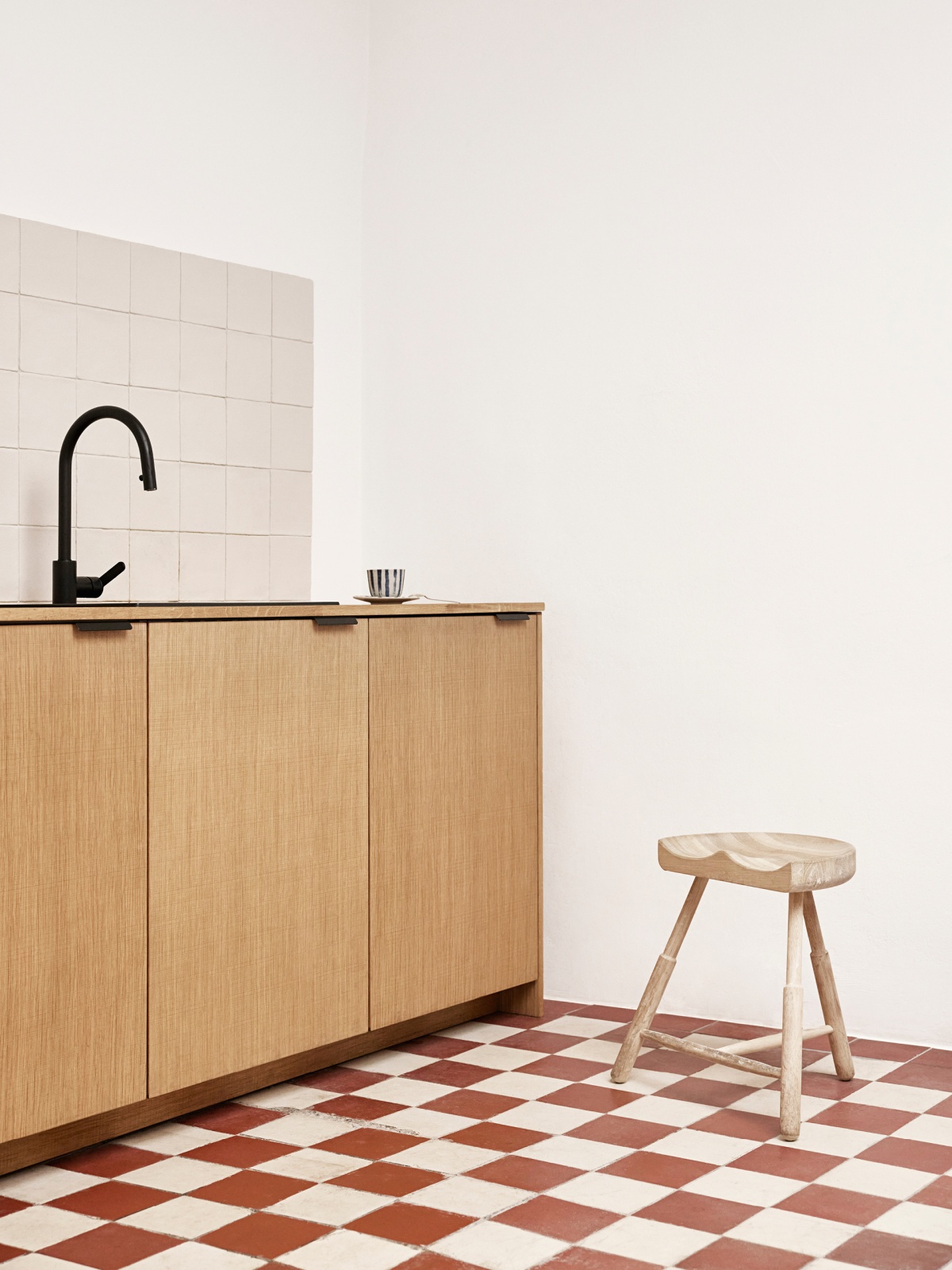 Kitchen with light wooden fronts and checkered floor