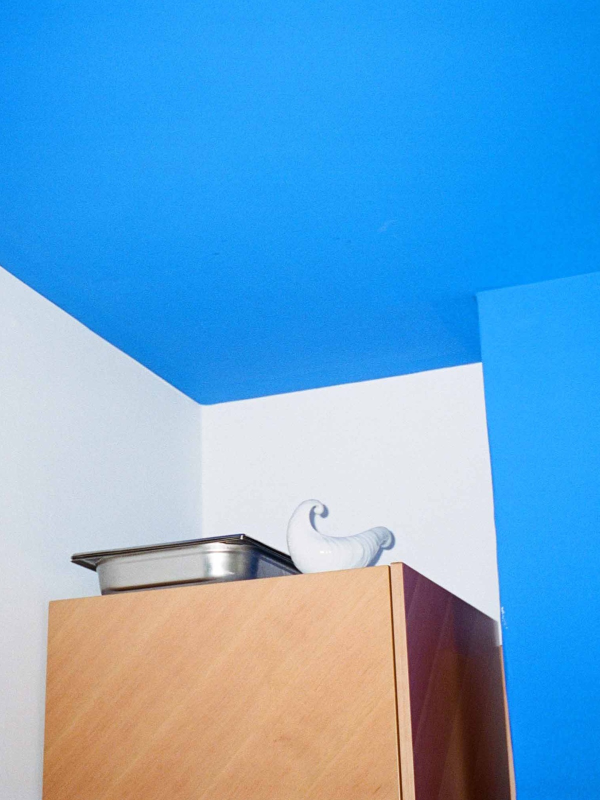 Wooden cabinet in room with blue ceiling and walls